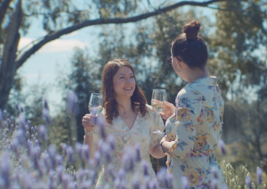 two ladies in lovely floral dresses drinking white wine in the lavender garden